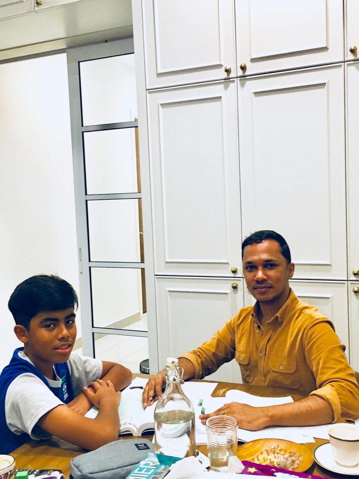 Mr Kumaraveelu teaching Mathematics one-to-one at a family table